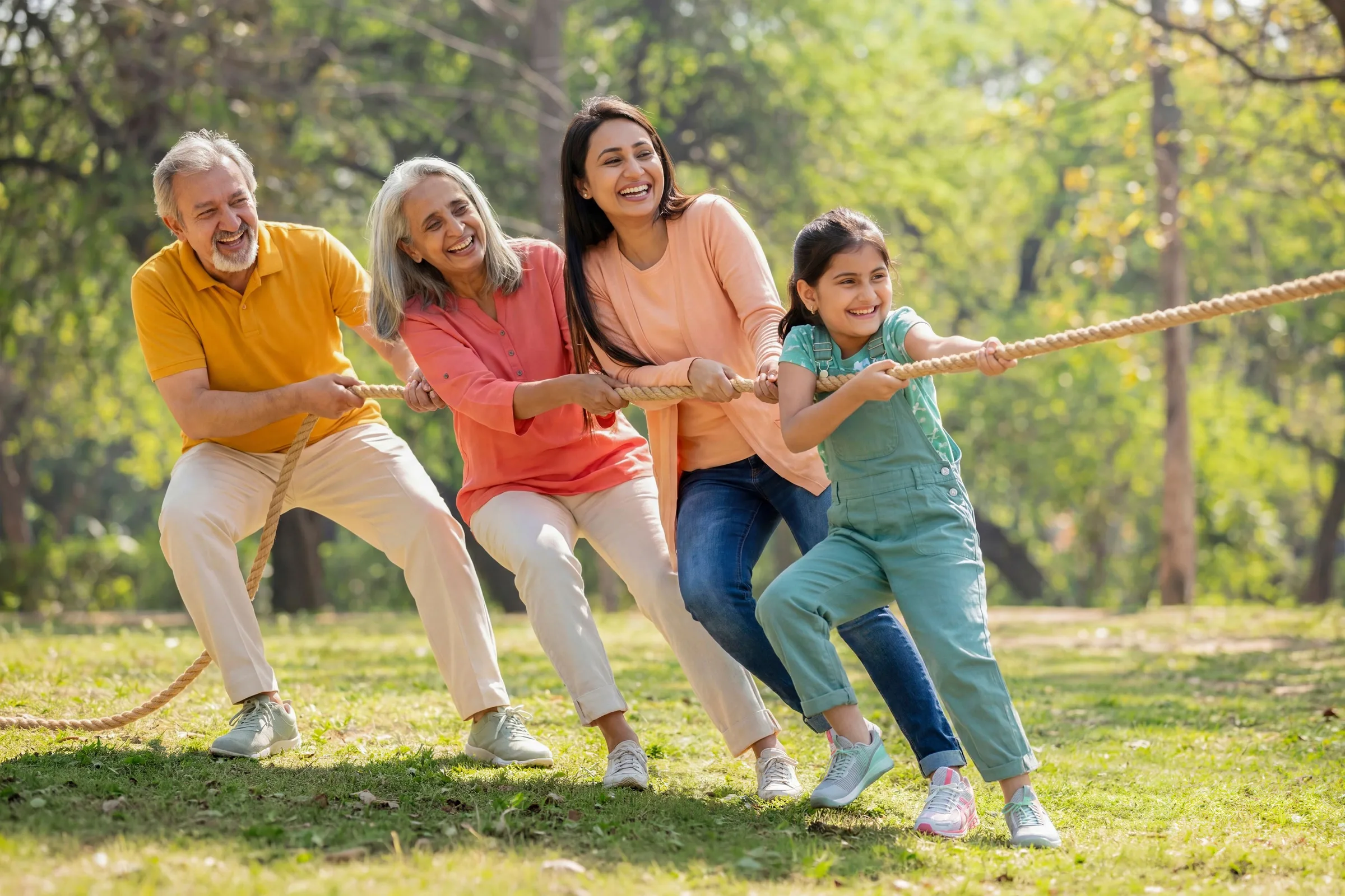 Three generations enjoying tug-of-war together on a lawn